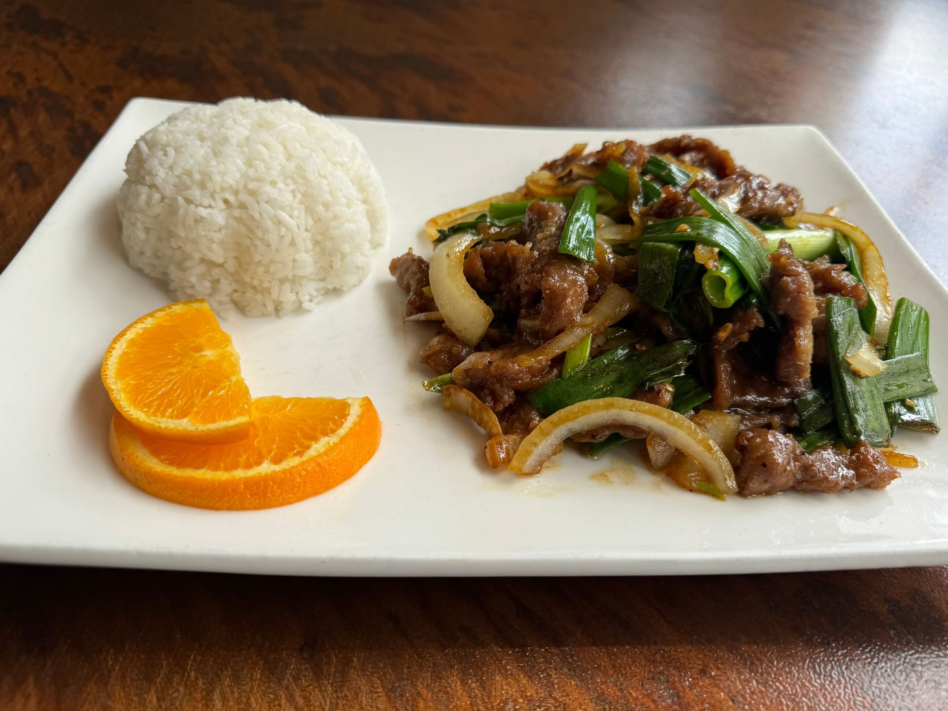 A plate of food with rice and oranges on a table.