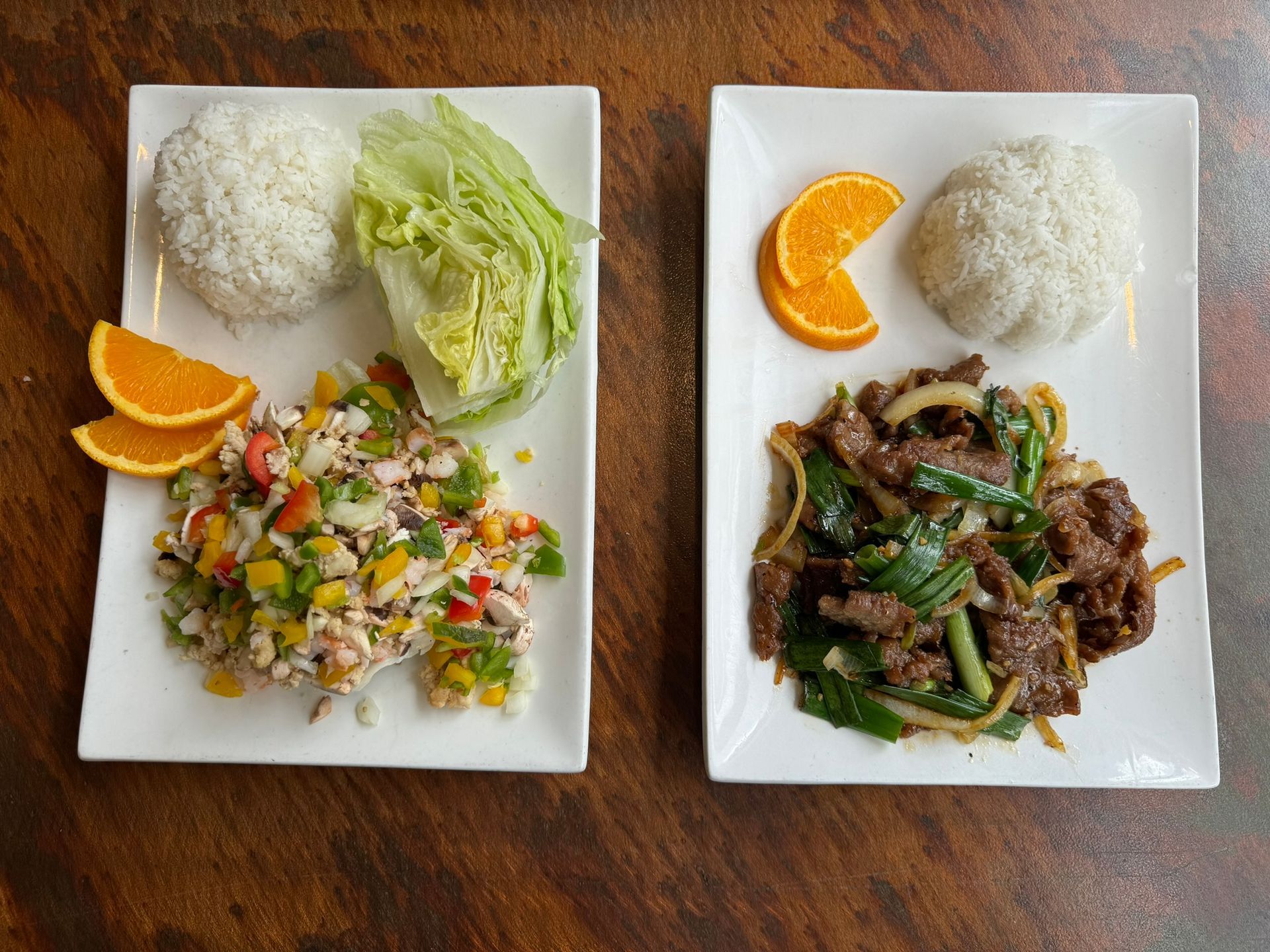 Two plates of food are sitting on a wooden table.
