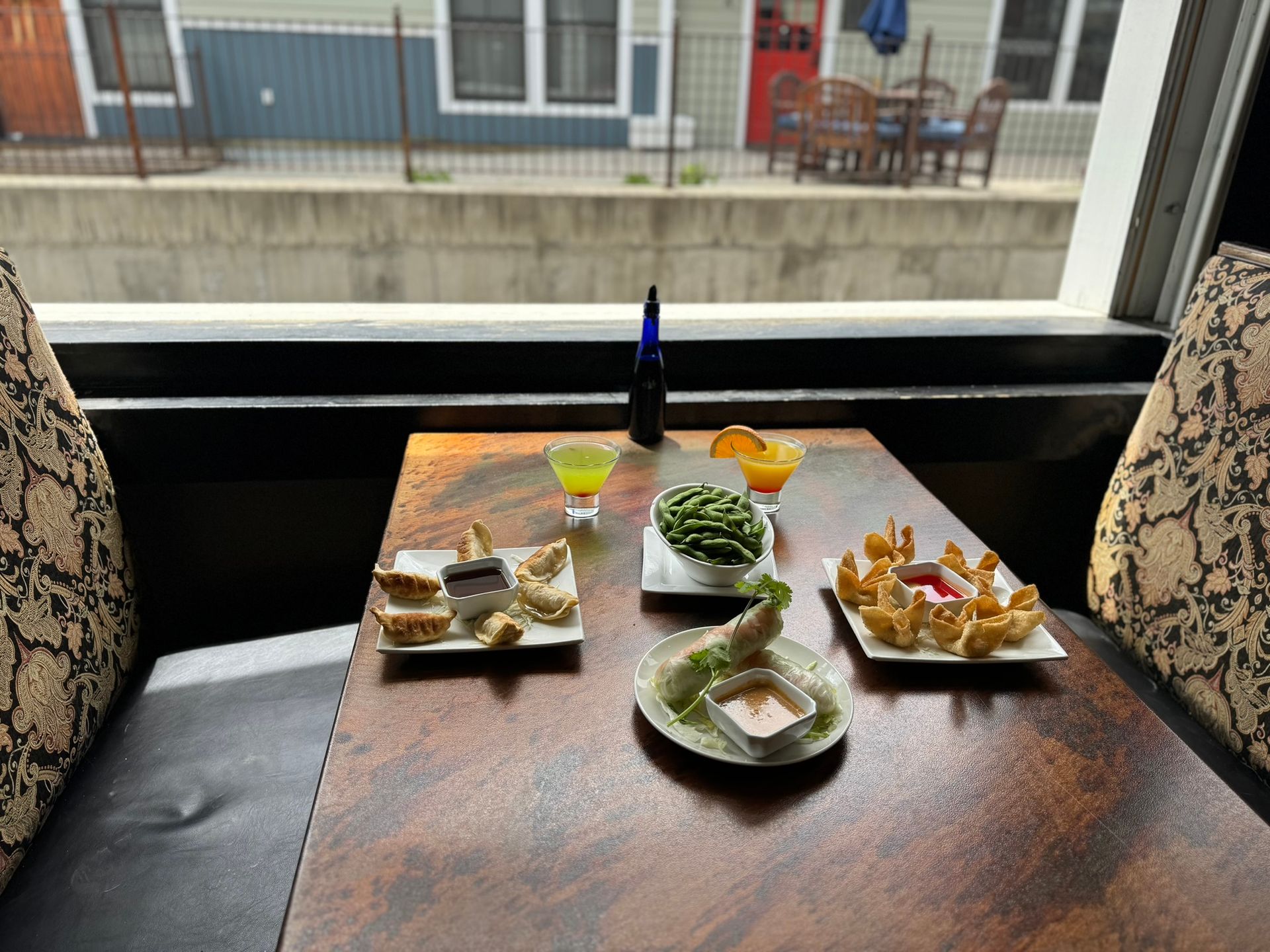 A table with plates of food and drinks on it in front of a window.