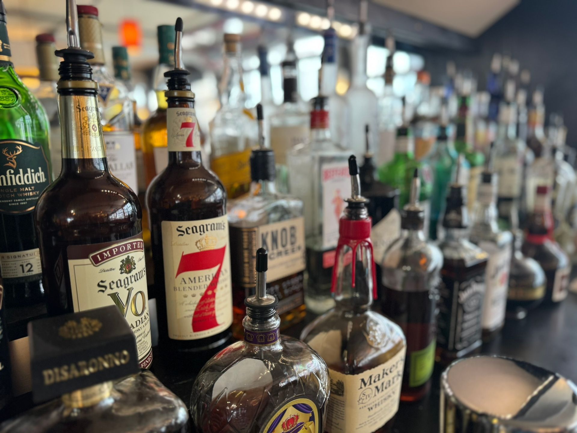 A row of bottles of liquor are lined up on a bar.