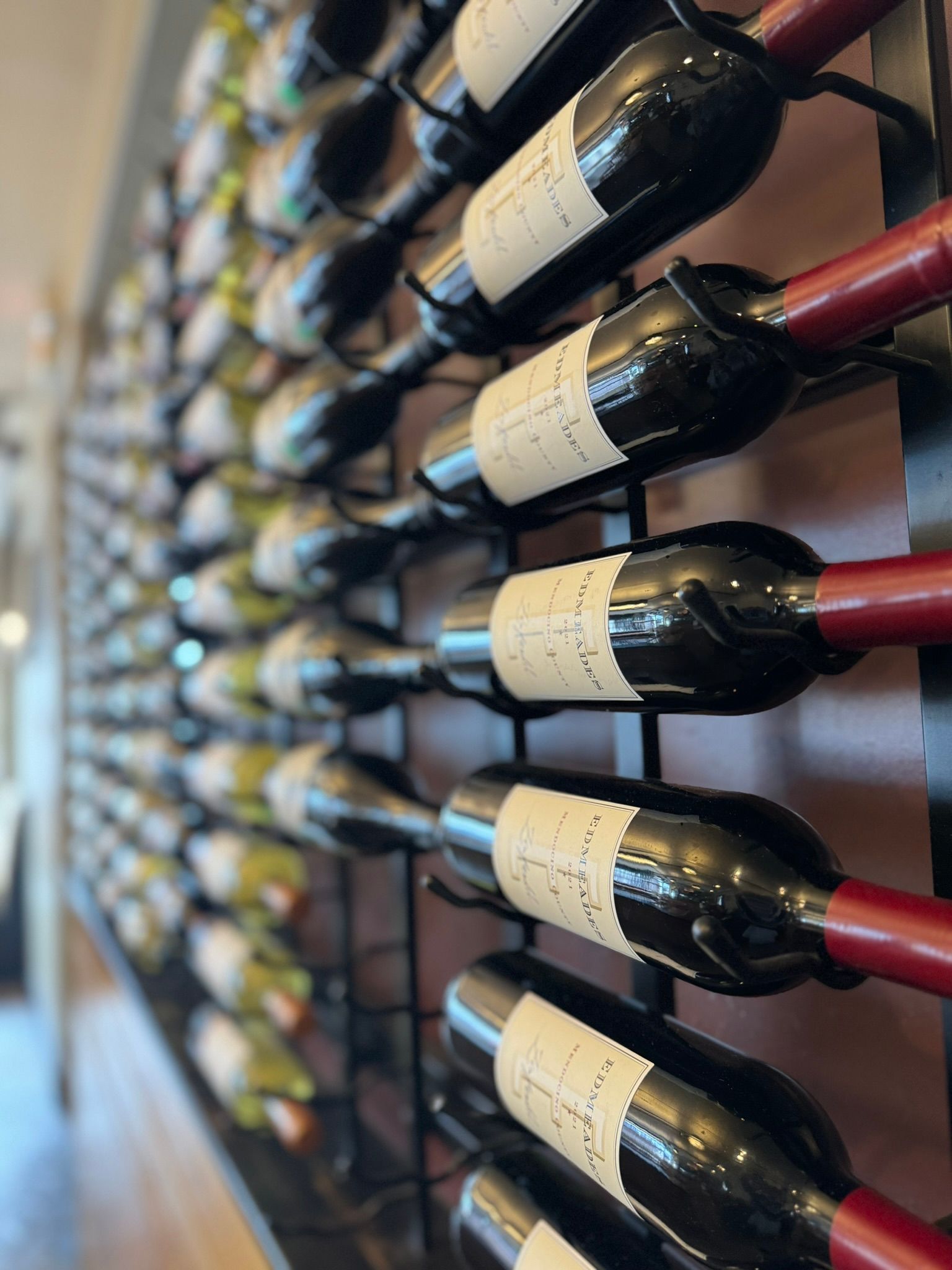 A row of wine bottles are lined up on a rack.