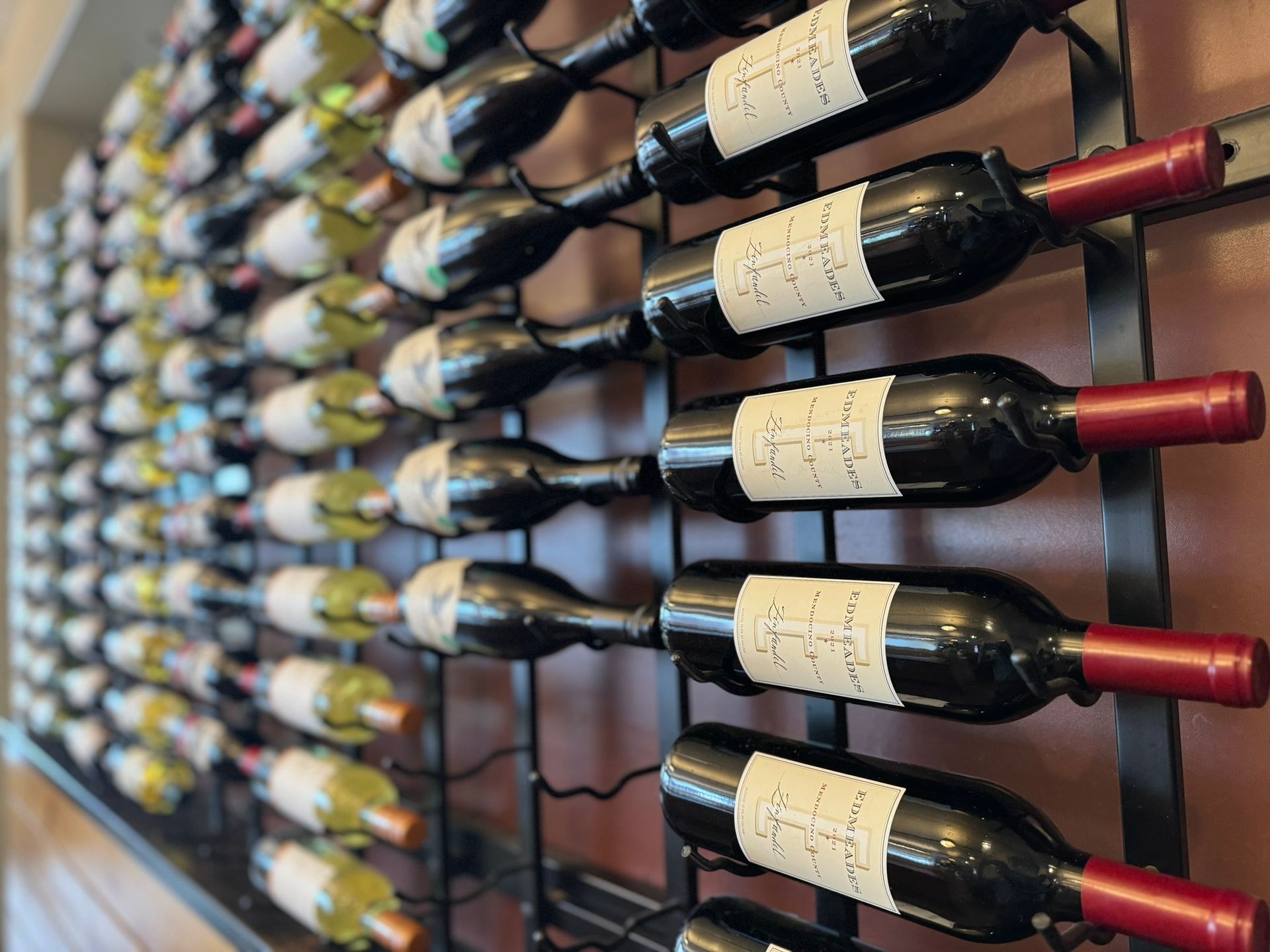 A row of wine bottles are lined up on a rack.