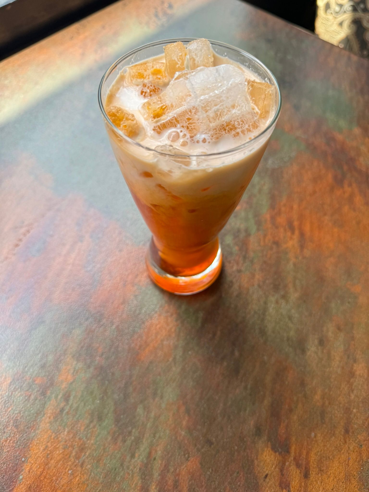 A glass of iced tea is sitting on a wooden table.