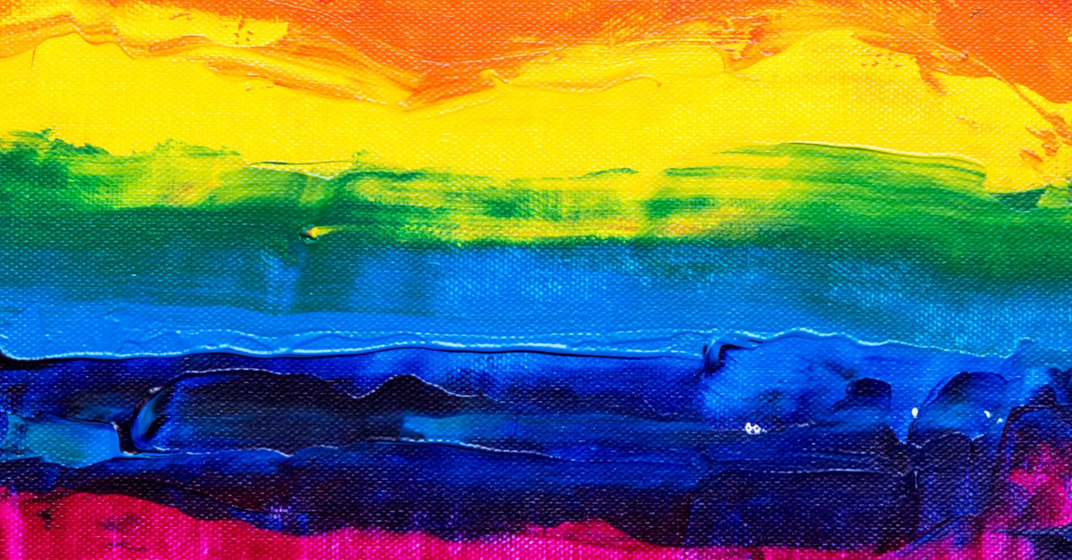 Close up image of paint on canvas in rainbow colours.