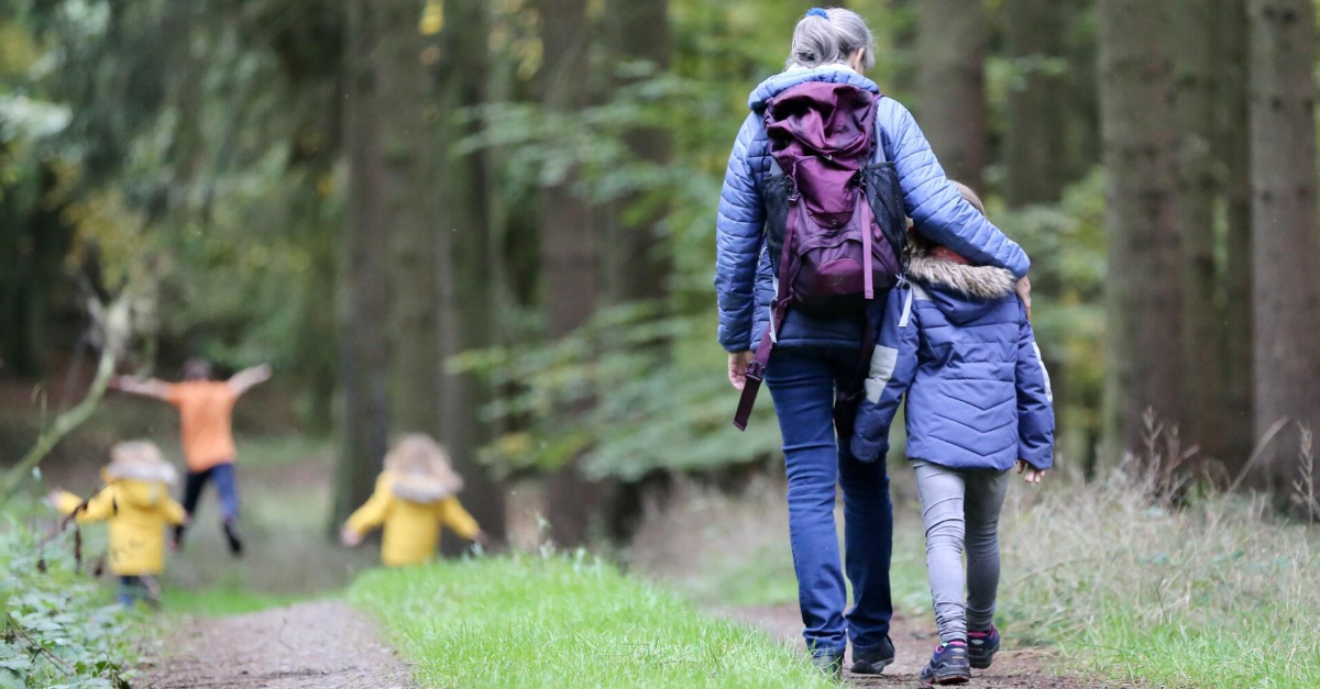 Parent and child walking down a nature path. Parent has their arm around the child's shoulders.