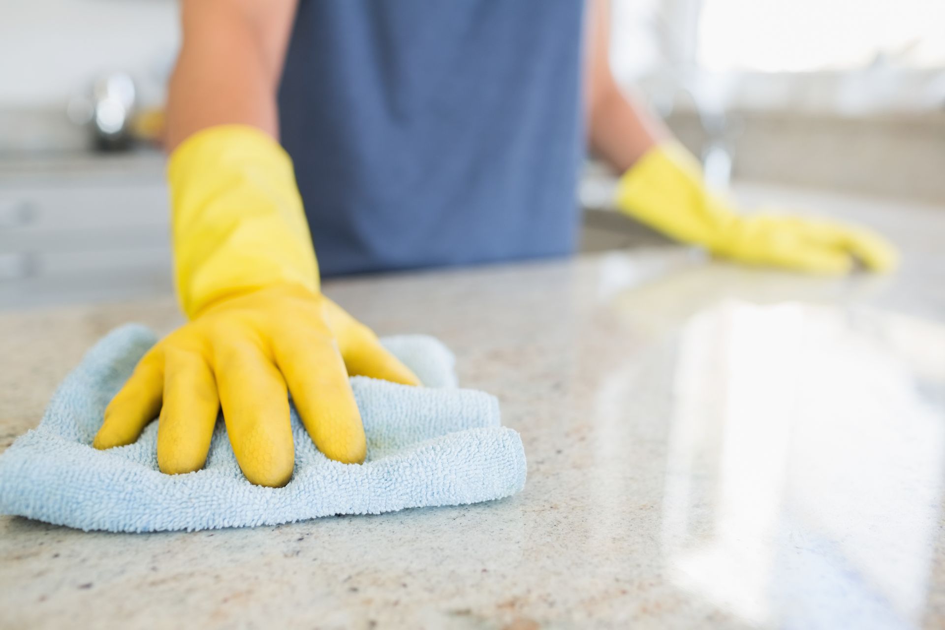 A woman diligently cleaning the kitchen counter with a cloth.