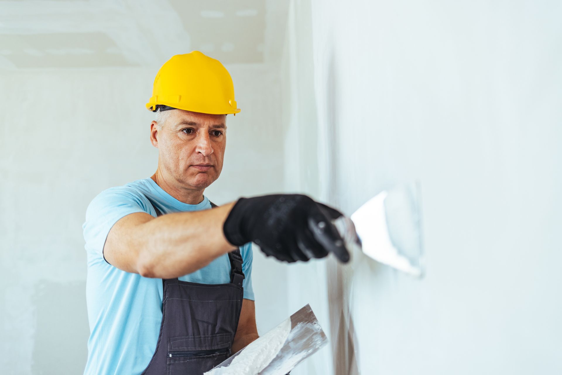 Construction worker applying plaster to interior wall.