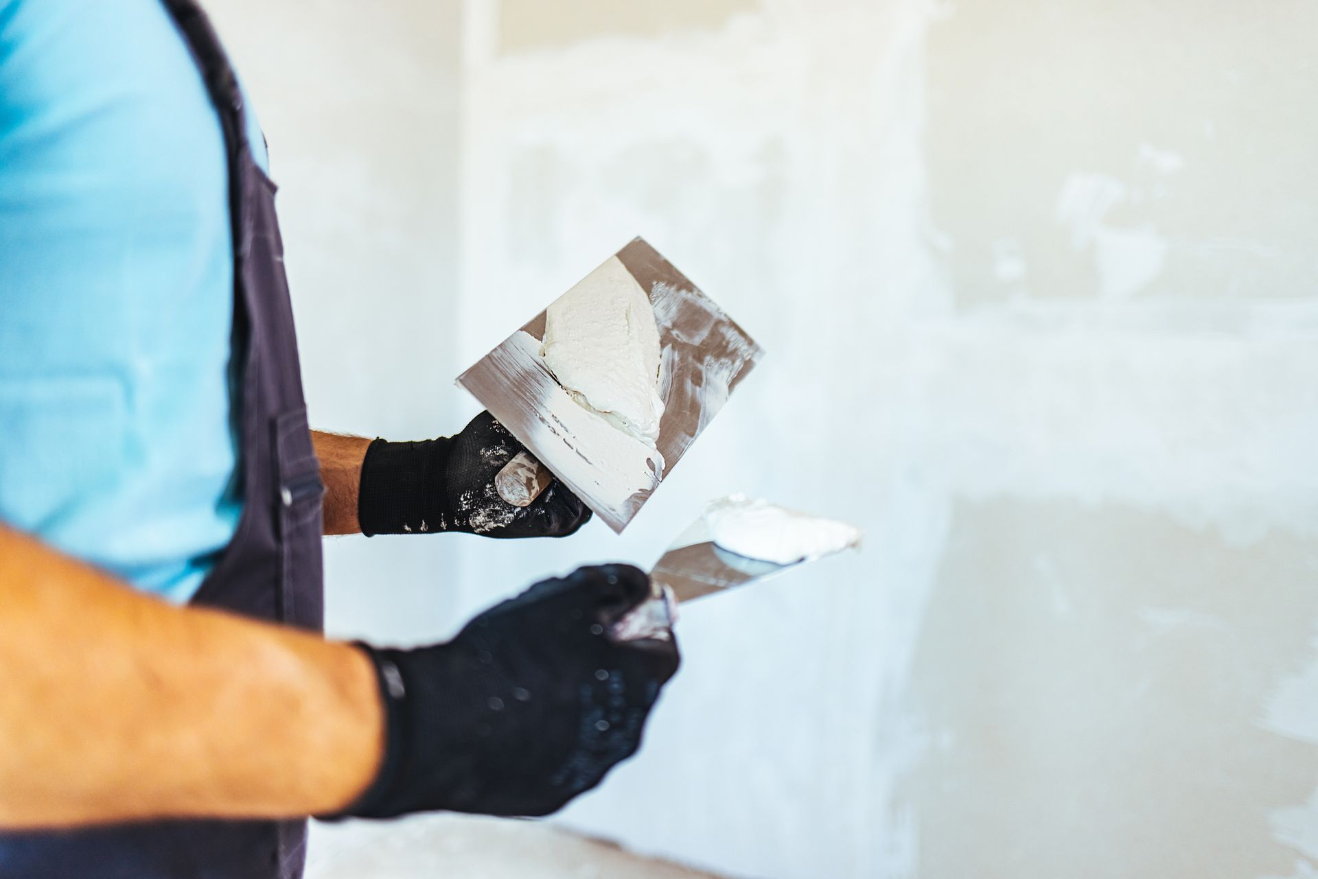 Close-up of worker holding plastering tools with white compound.
