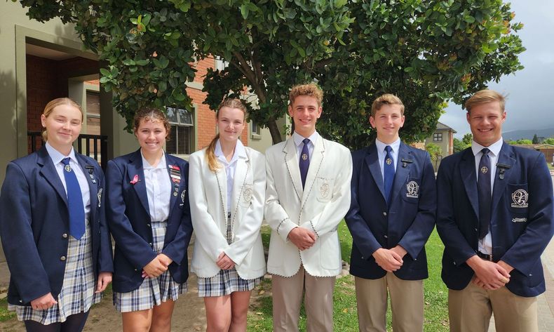 a group of young people in school uniforms are posing for a picture .