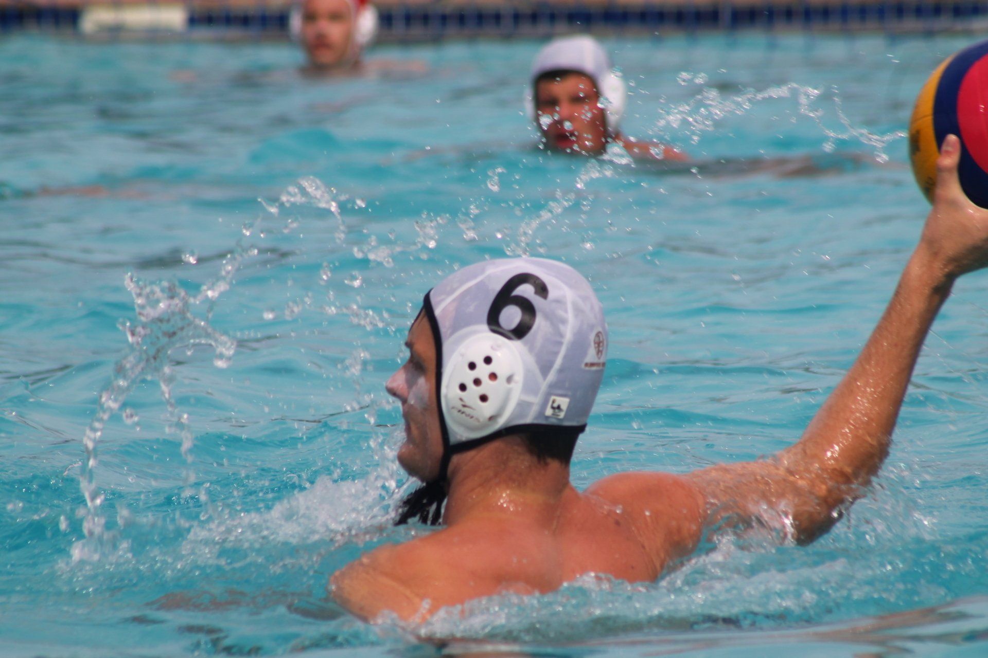 a boy is playing water polo in a swimming pool .