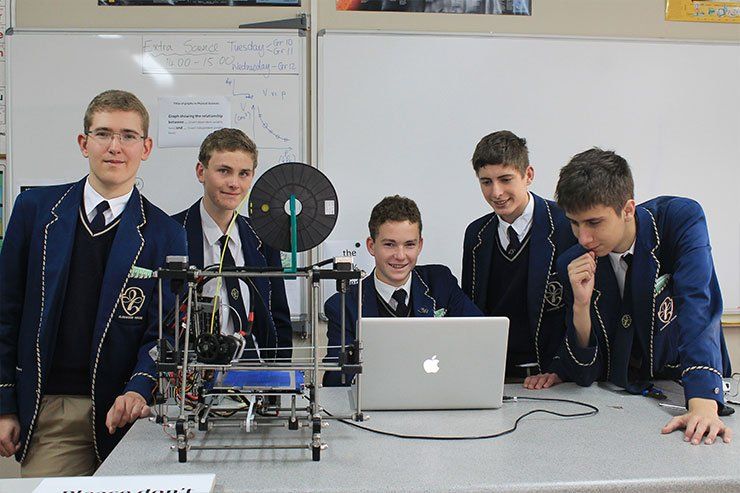 a group of boys are standing around a laptop computer