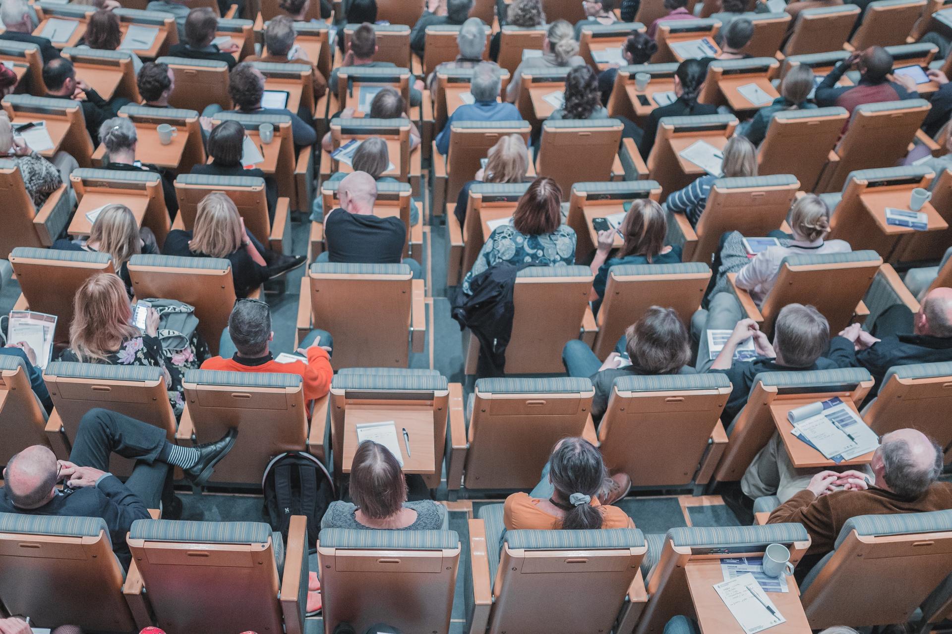 A large group of people are sitting in a lecture hall.