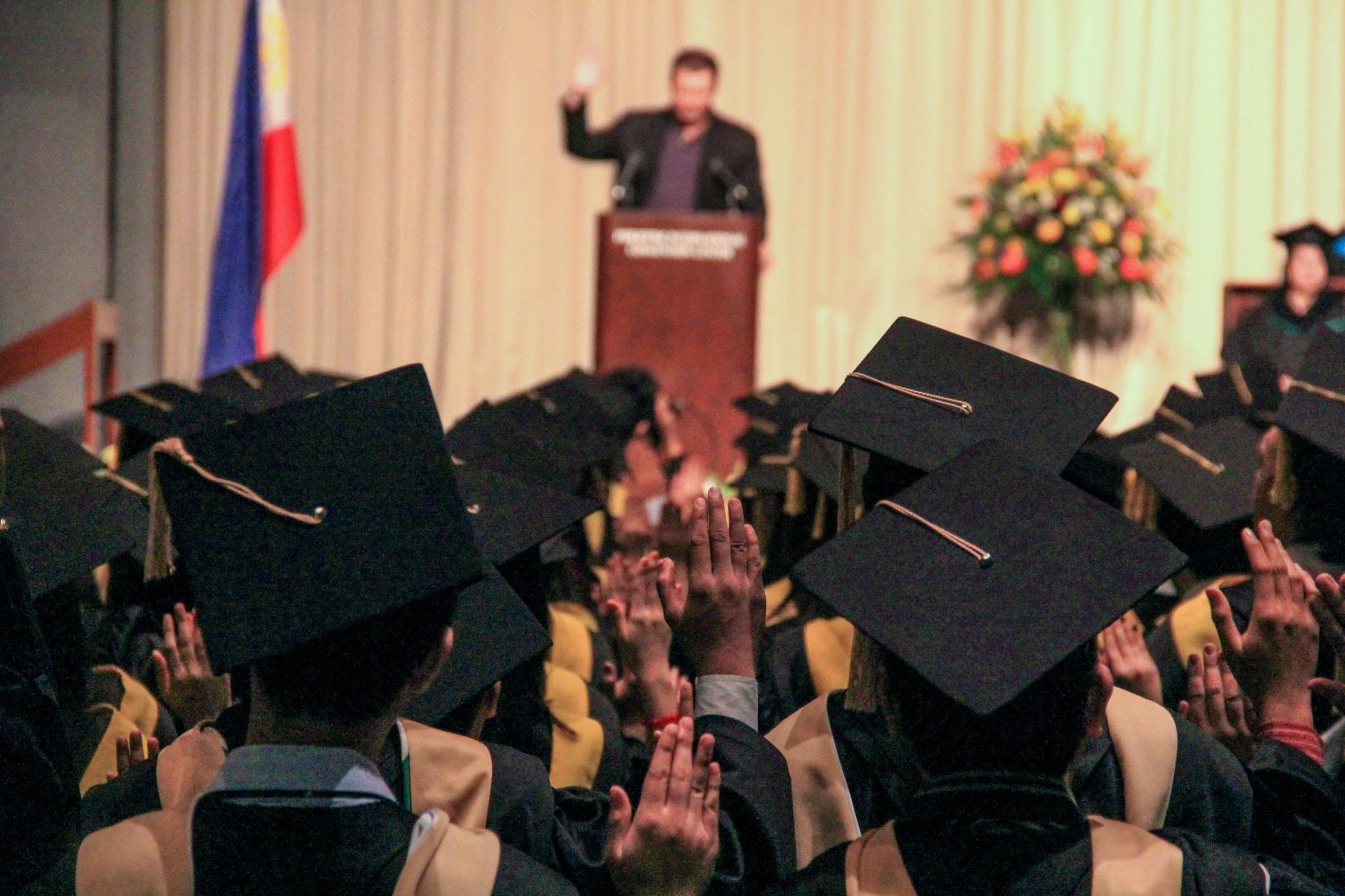 A group of graduates are raising their hands in the air at a graduation ceremony.