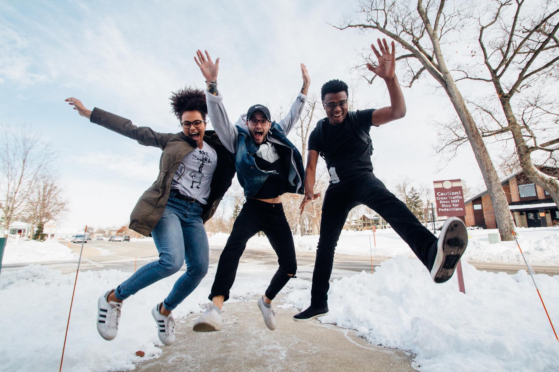 Three people are jumping in the air in the snow.