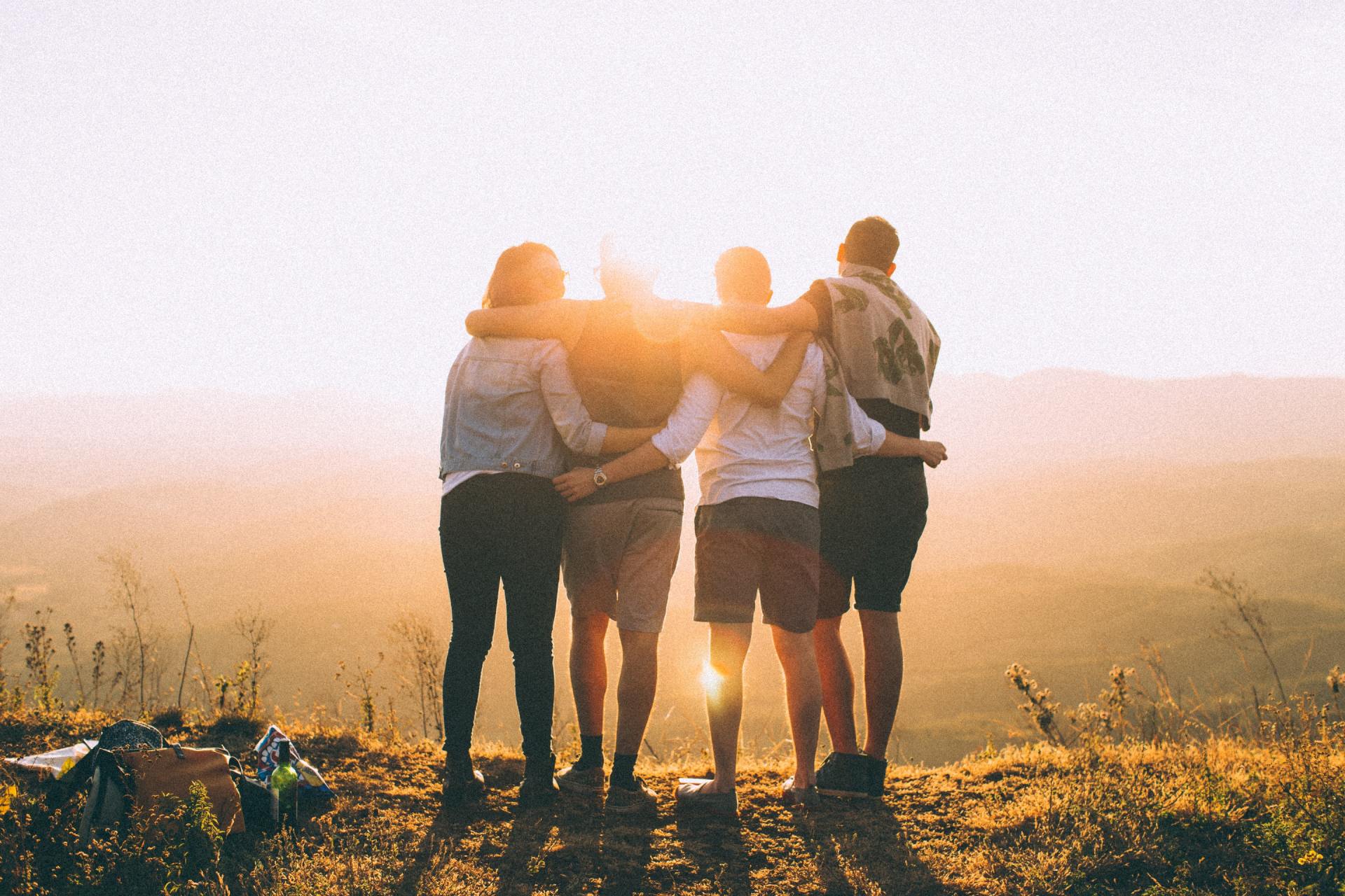 A group of people are standing on top of a hill with their arms around each other.