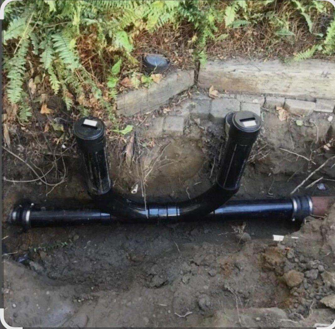 Black irrigation pipe assembly in a trench with sprinkler heads.