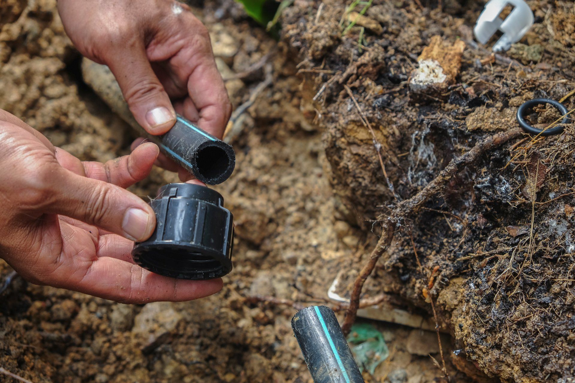 Black irrigation pipe assembly in a trench with sprinkler heads.