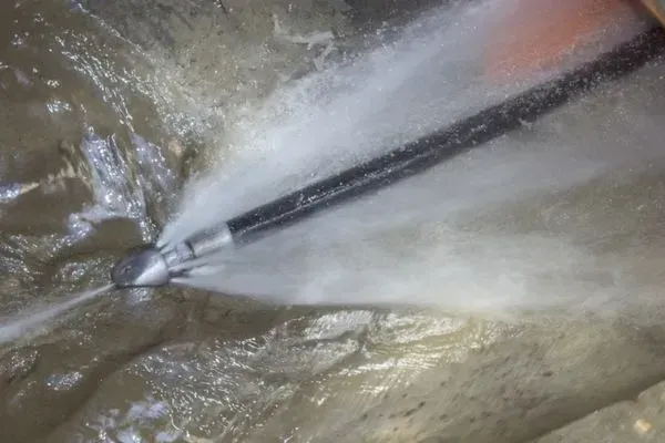 Bathroom plumbing exposed, showing black drain pipes, a red drain cap, and insulation foam.