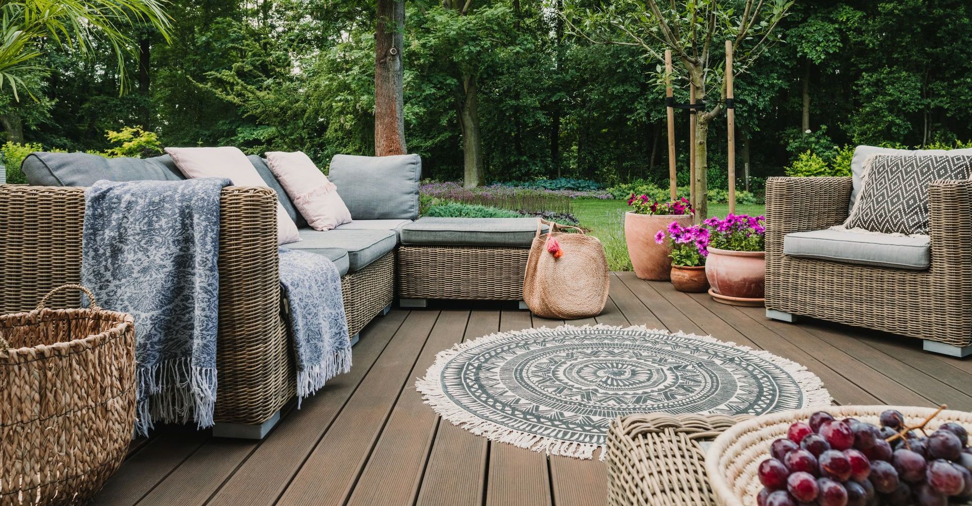 A wooden deck with wicker furniture and a basket of grapes.