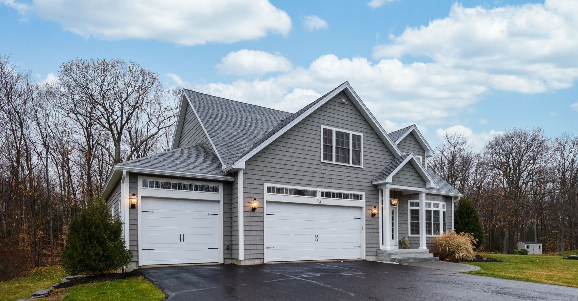A large house with two garage doors and a driveway in front of it.