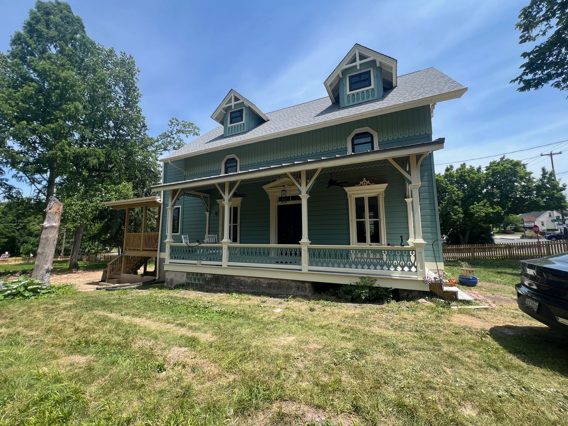 A blue house with a porch and a truck parked in front of it.