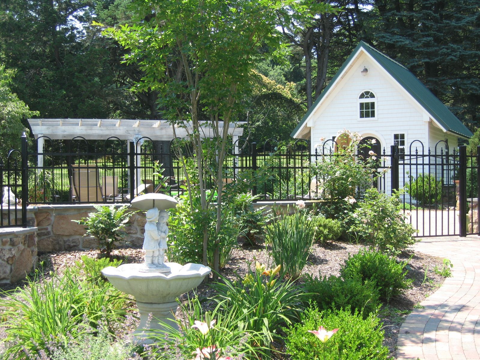 A white house with a green roof and a fountain in front of it