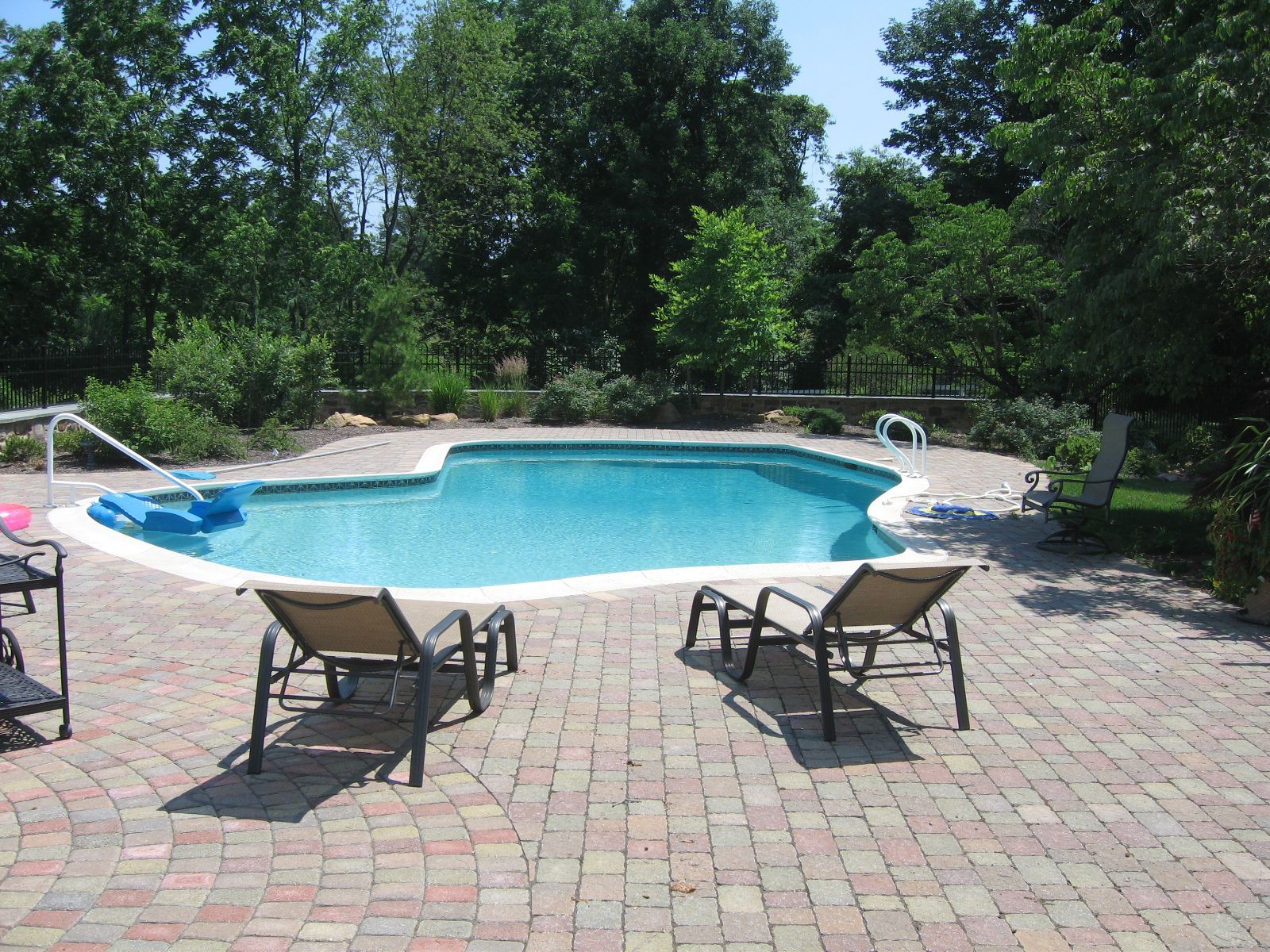 A large swimming pool surrounded by chairs and trees