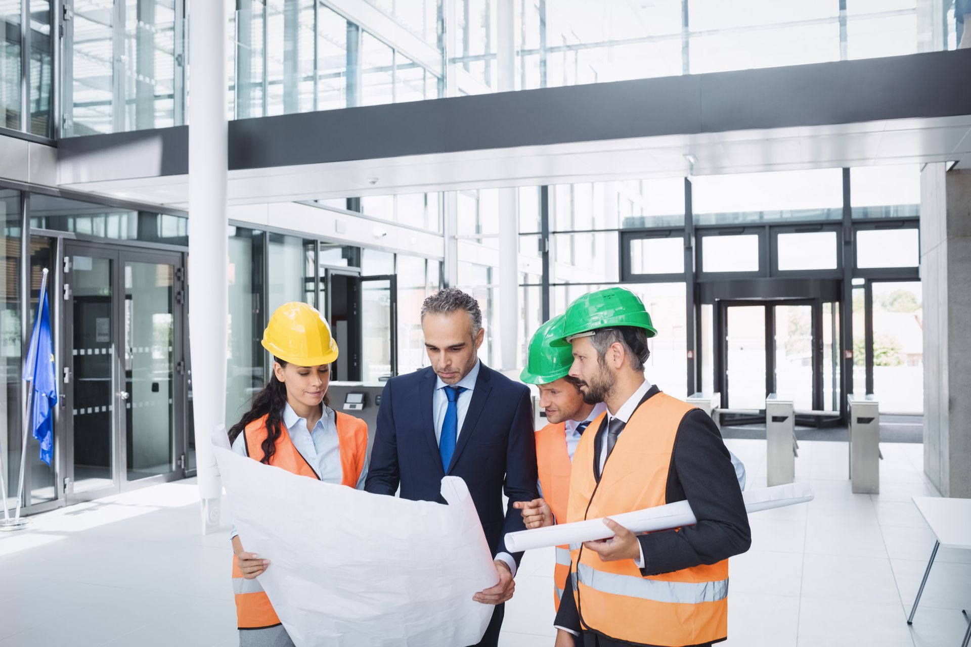 A group of construction workers are looking at a blueprint in a building under construction.