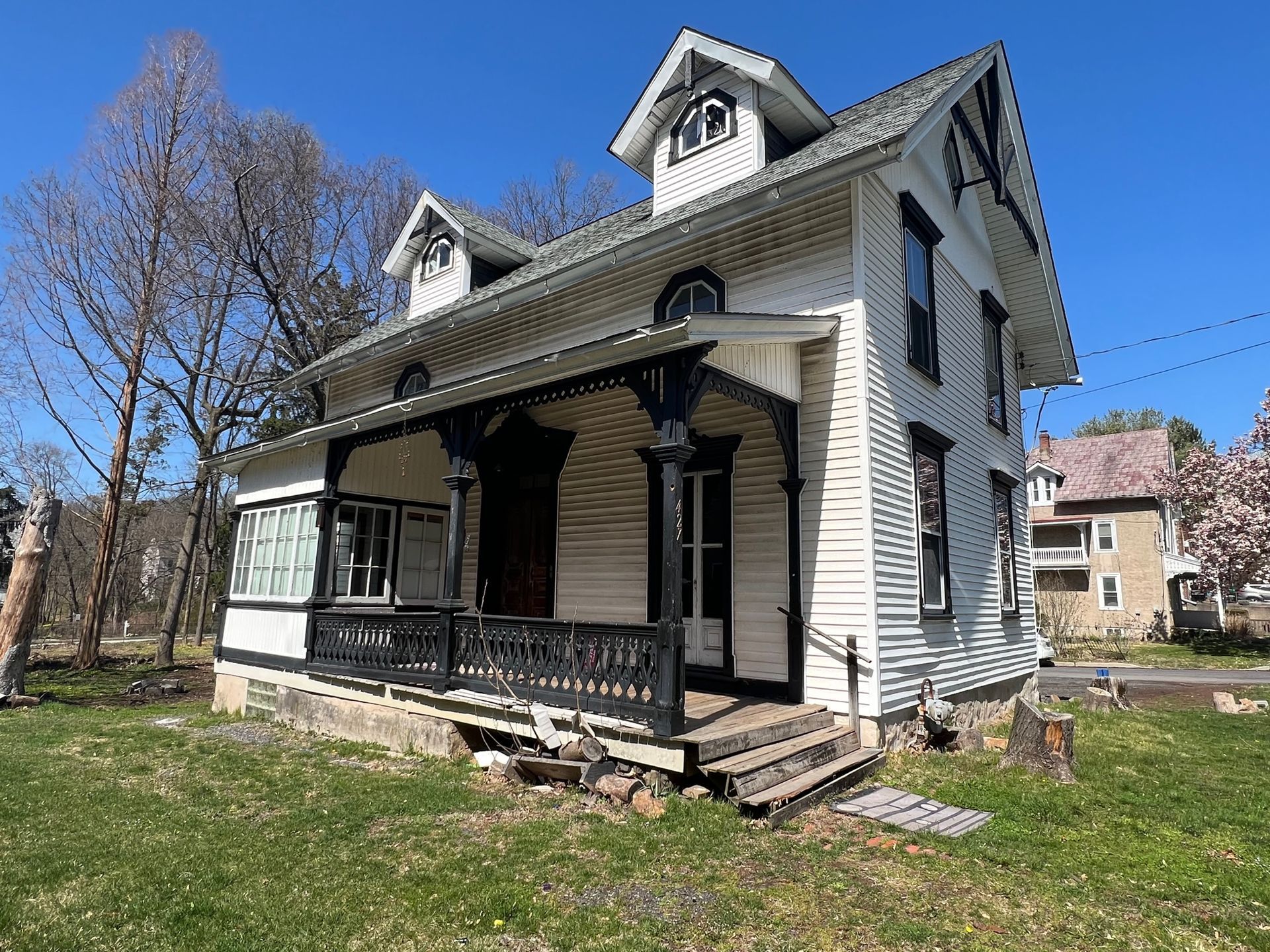 A white house with a black porch and a blue sky in the background.