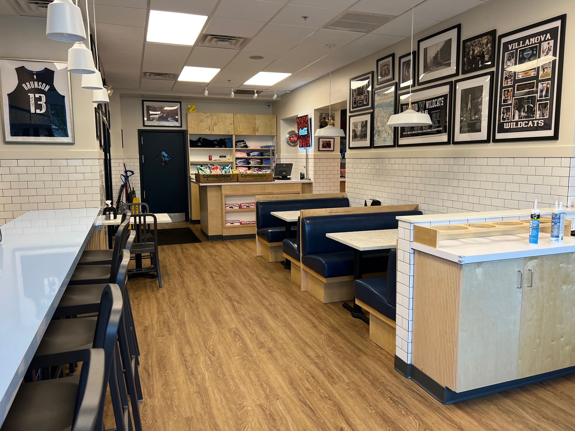Interior of a restaurant. Booth seating, a bar, and framed photos line the walls.