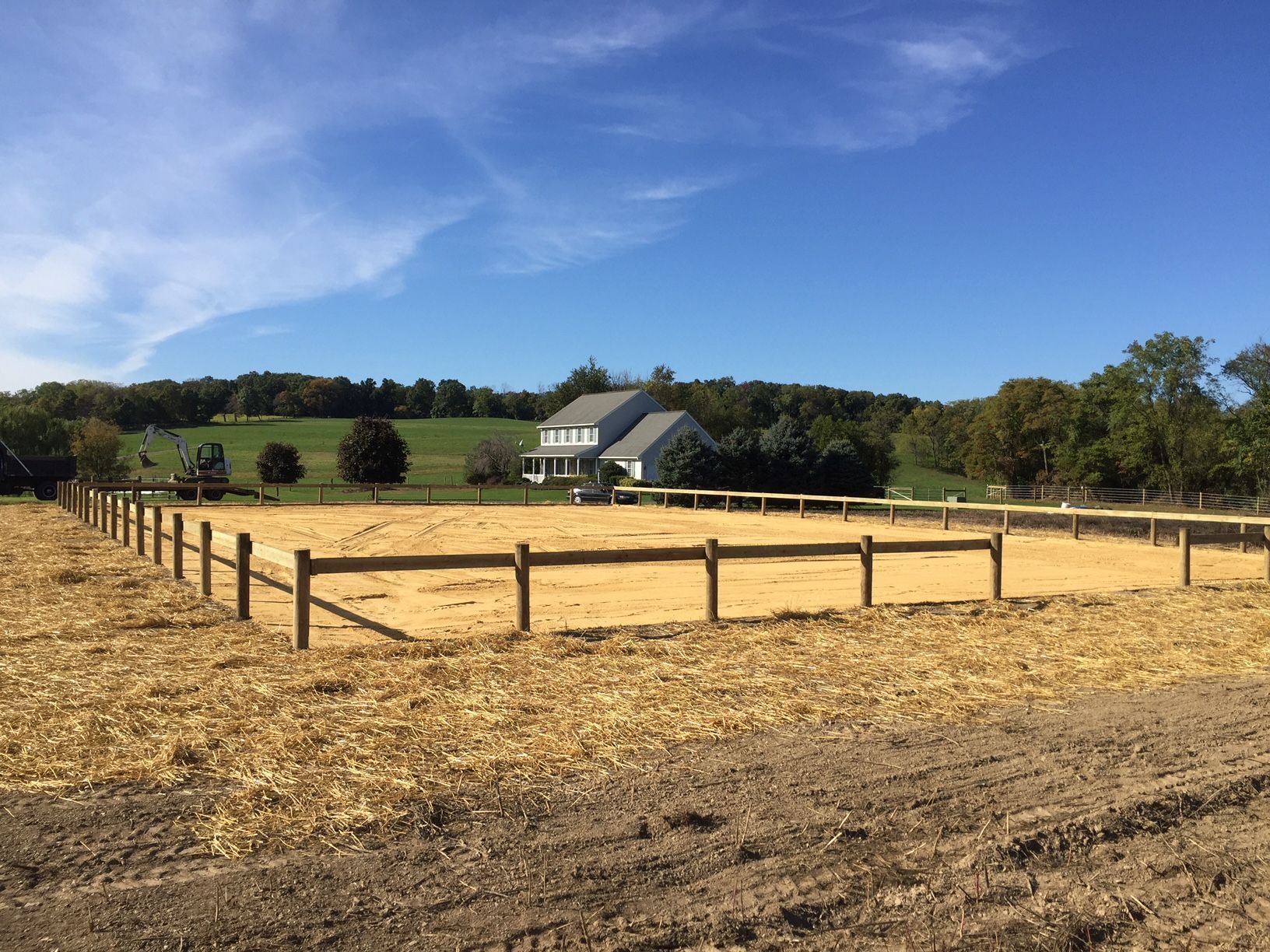 A field with a fence and a house in the background