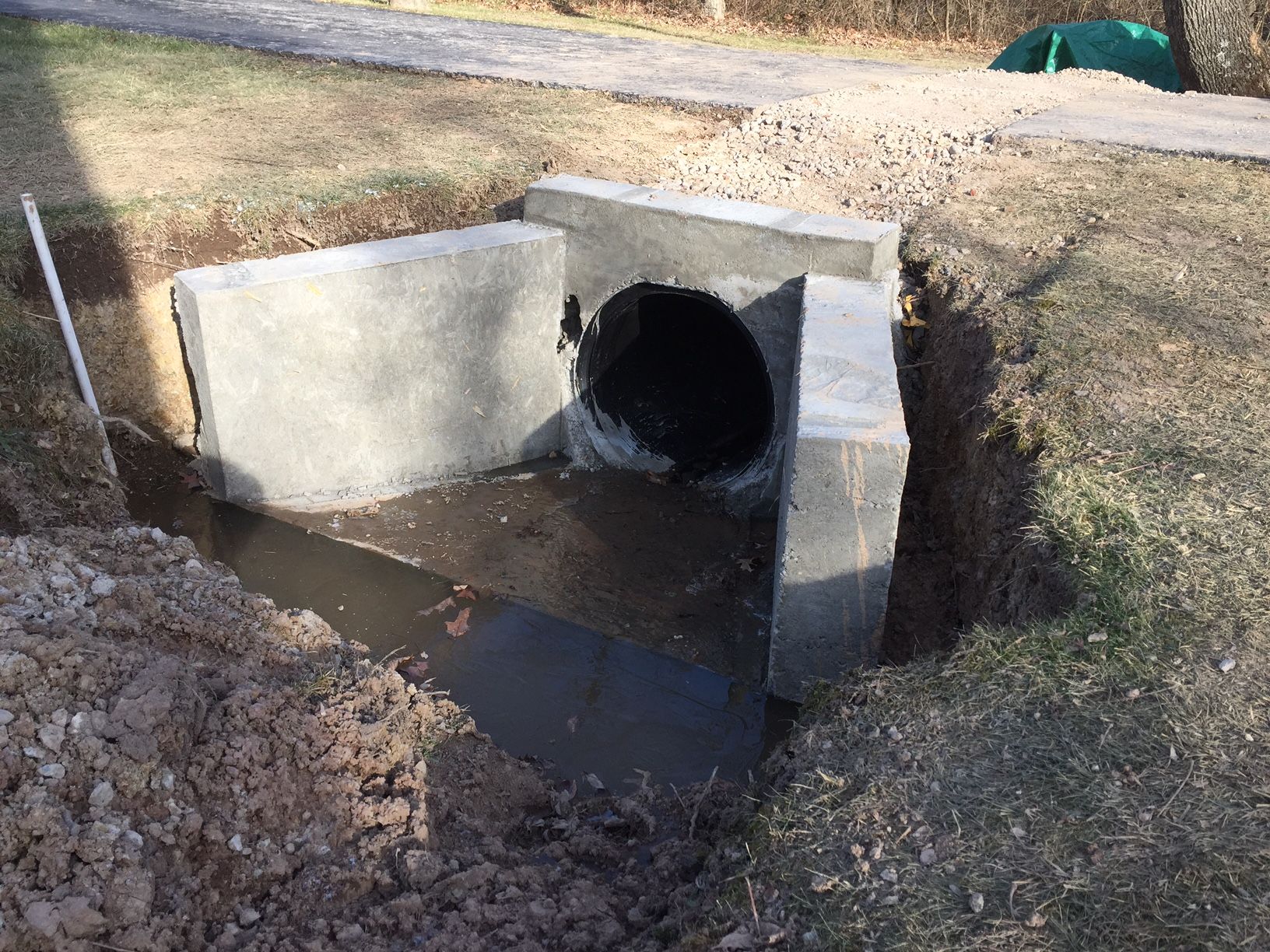 A large pipe is coming out of a hole in the ground.