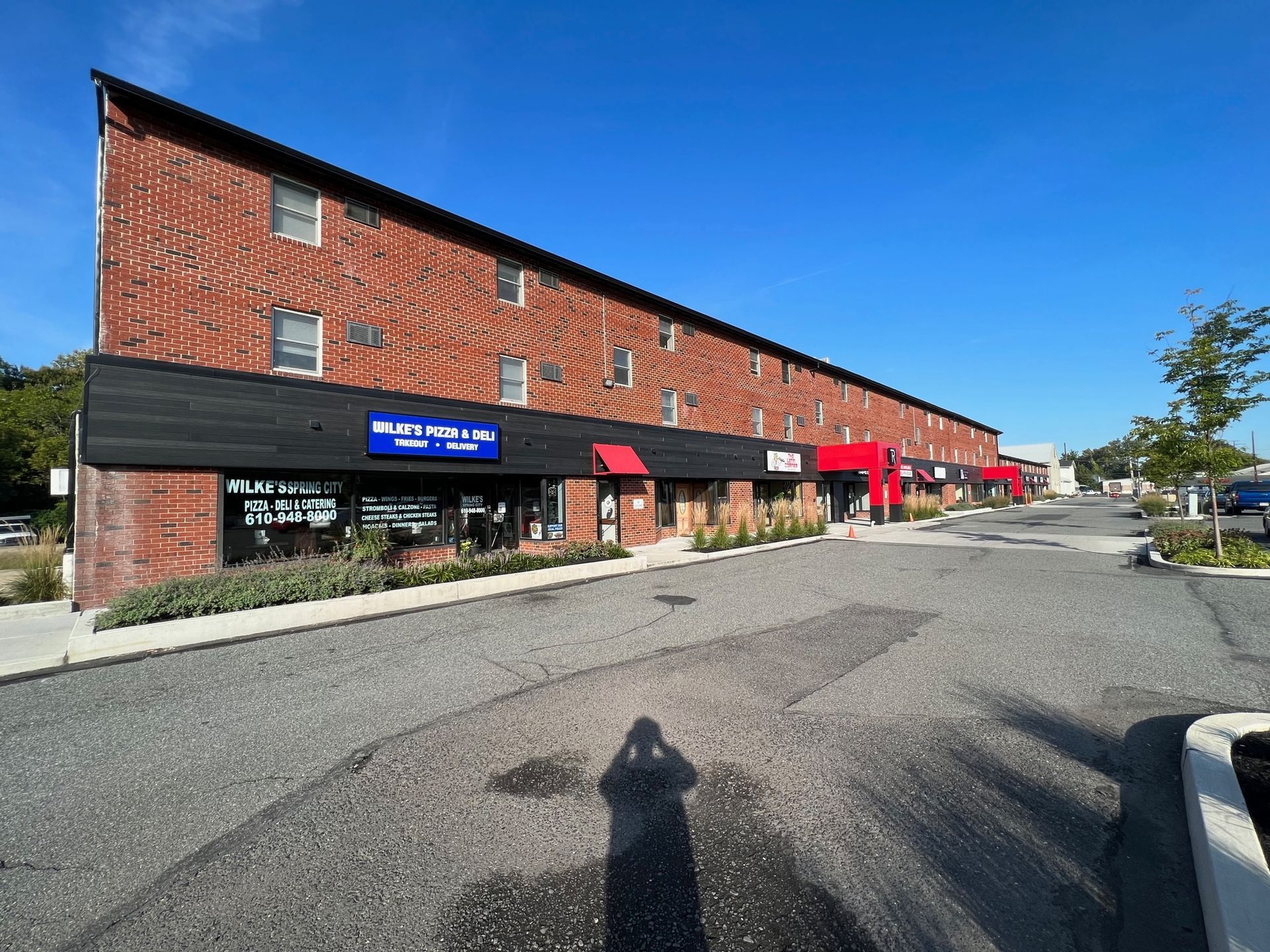 A large brick building with a lot of windows and a parking lot in front of it.