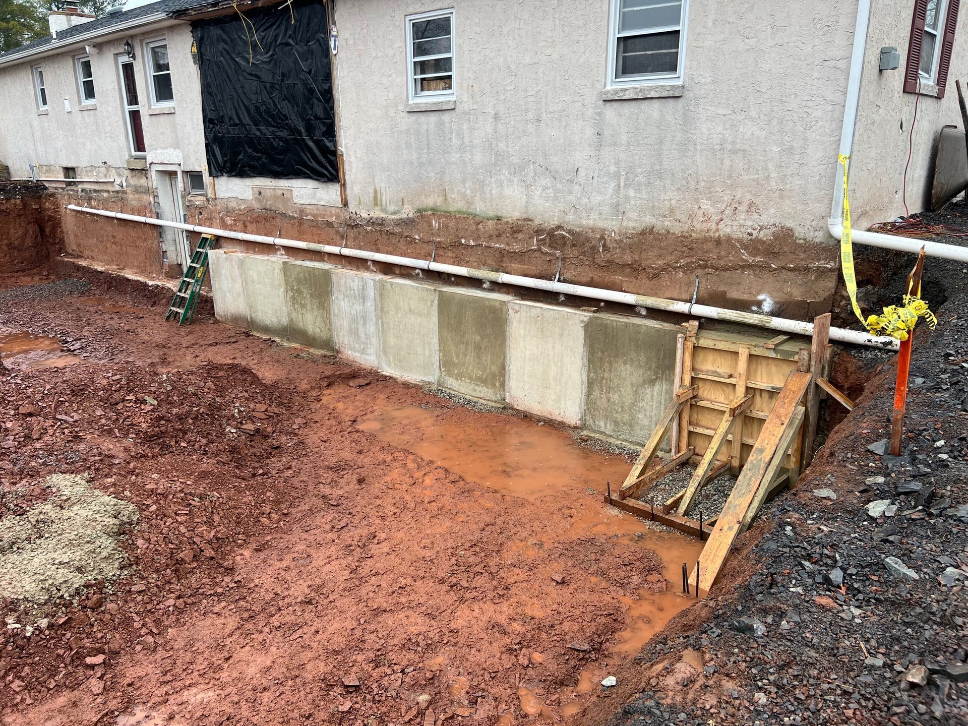 A large pile of dirt is sitting next to a brick wall.