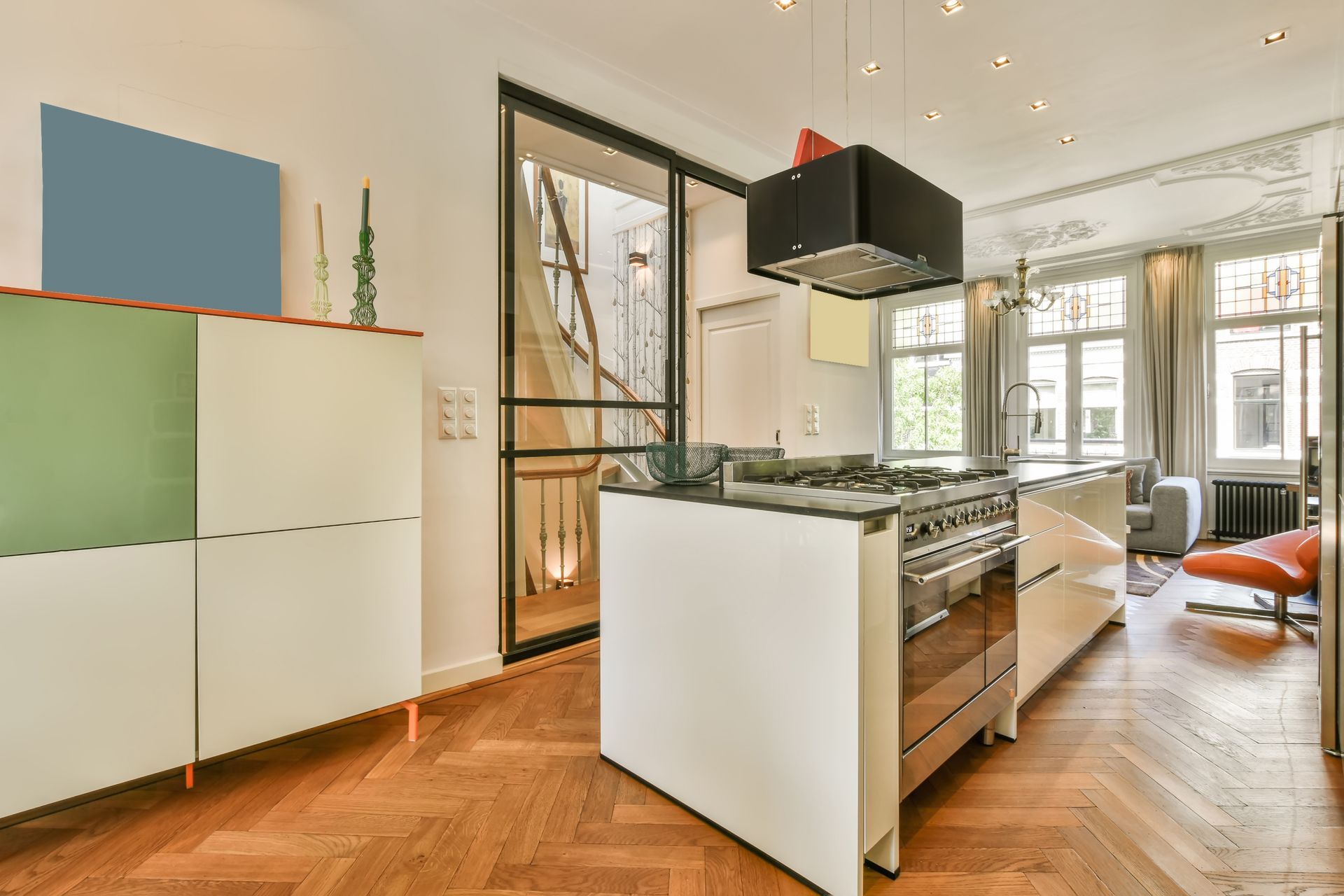 Modern kitchen with island, stove, cabinets, and a doorway to stairs.
