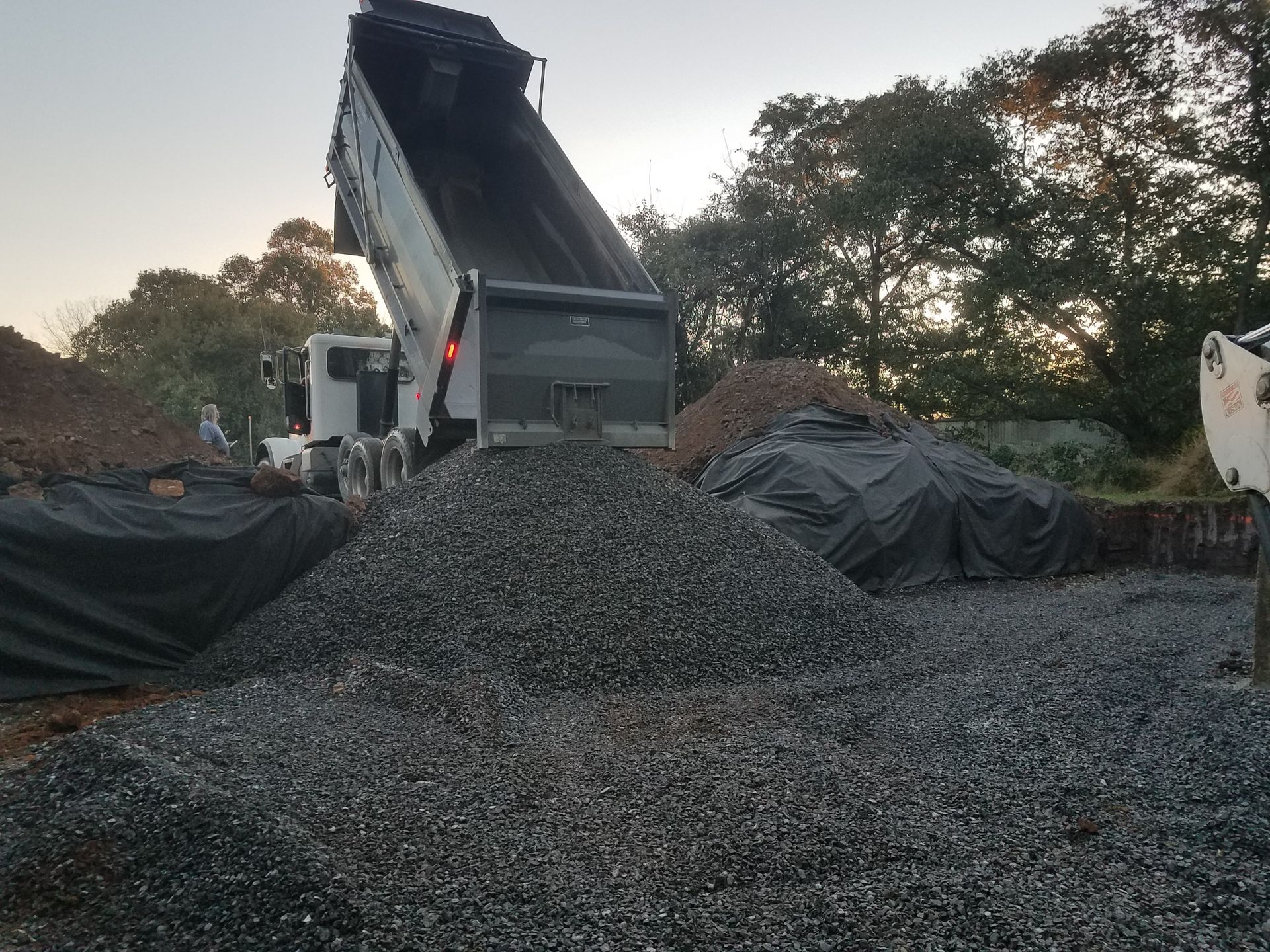 A dump truck is dumping gravel into a pile.