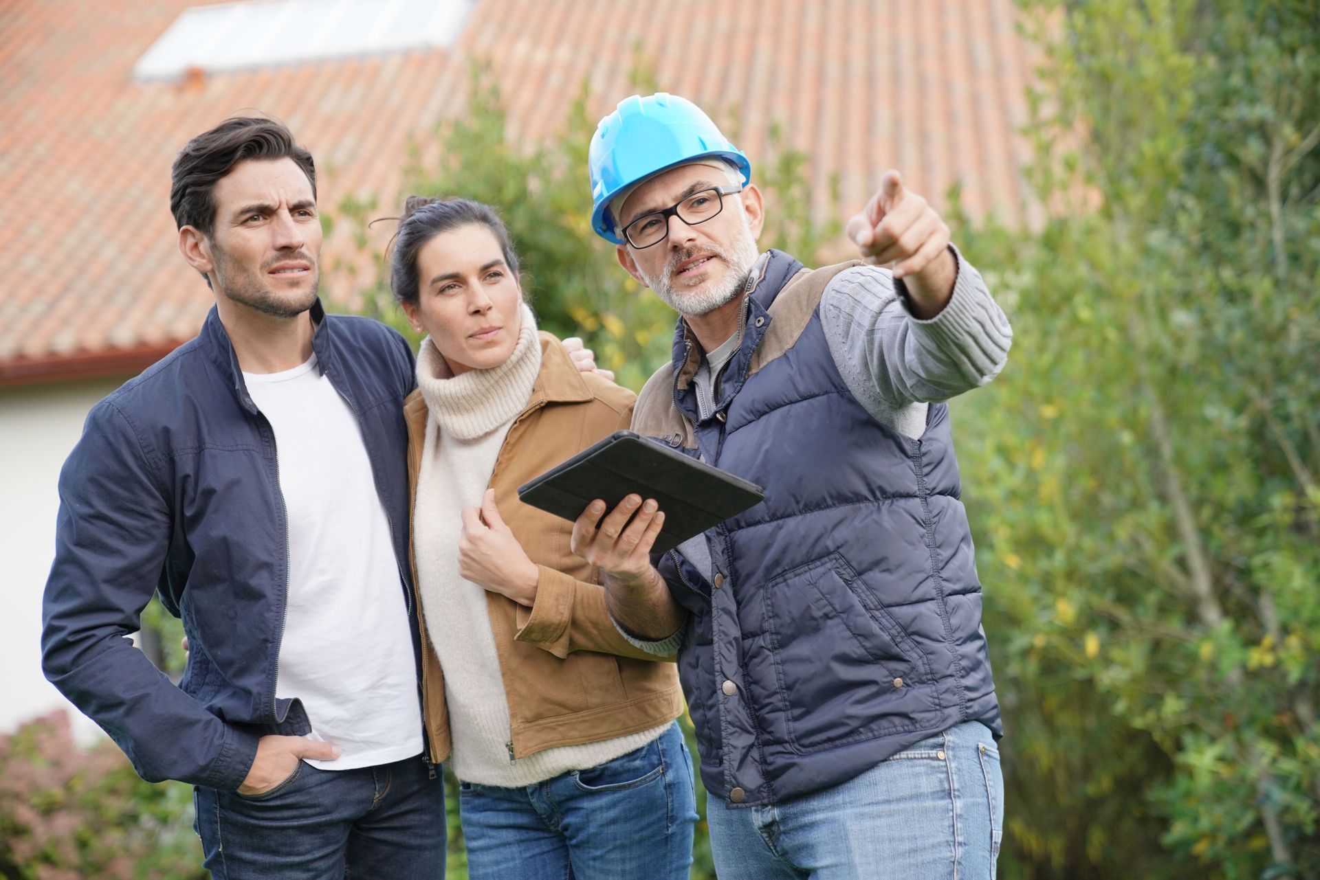 A man and a woman are standing next to a man holding a tablet.