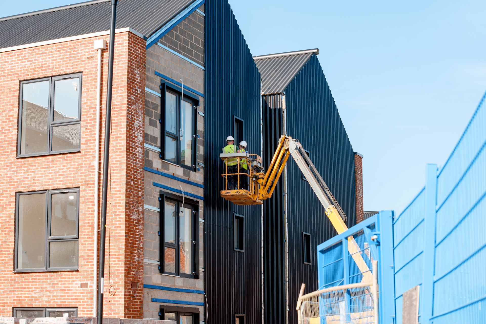 Two construction workers are working on the side of a building.