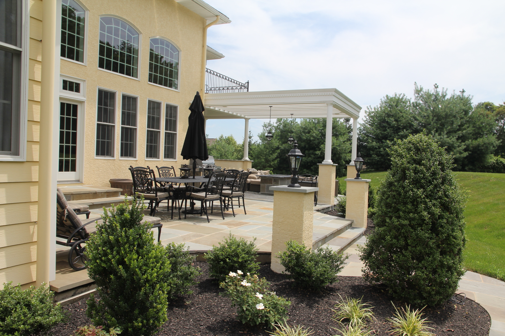 A large yellow house with a patio area with tables and chairs