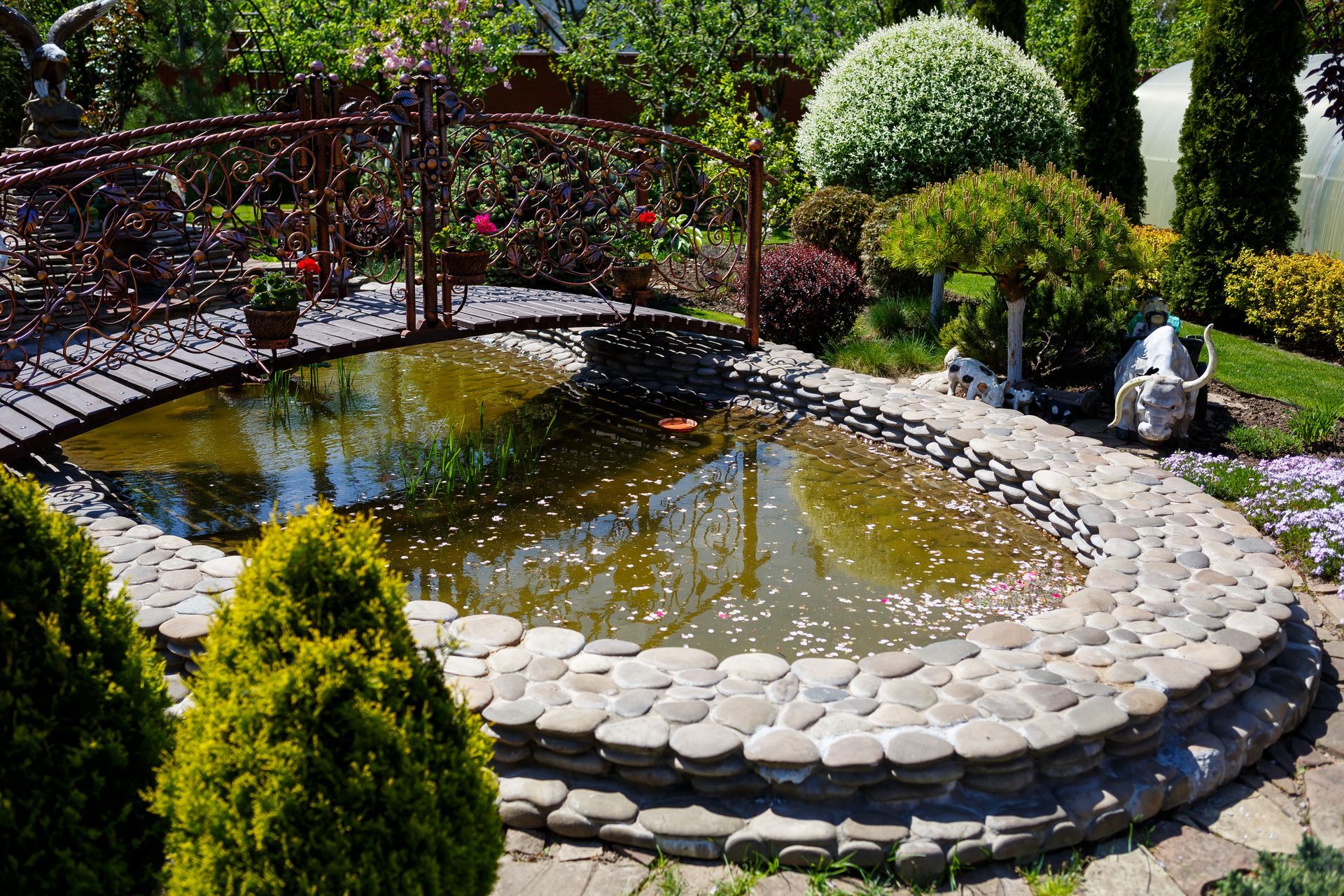 There is a pond in the middle of the garden with a bridge over it.