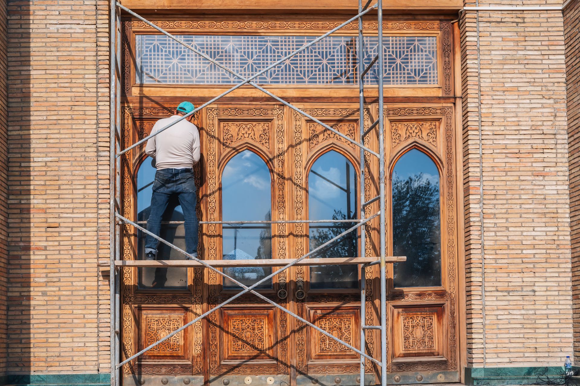 A man is standing on a scaffolding next to a wooden door.