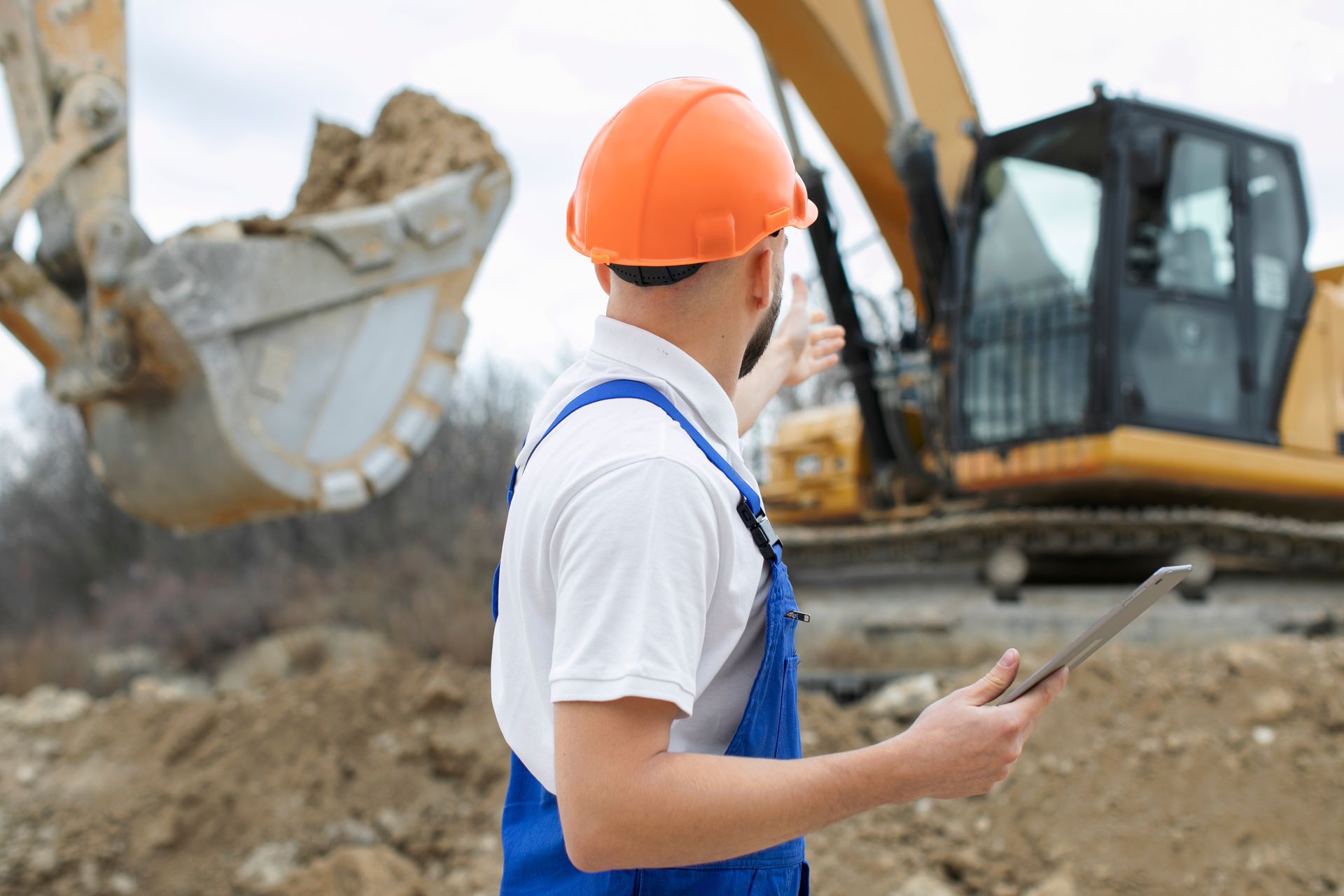 A construction worker is looking at a tablet in front of a bulldozer.