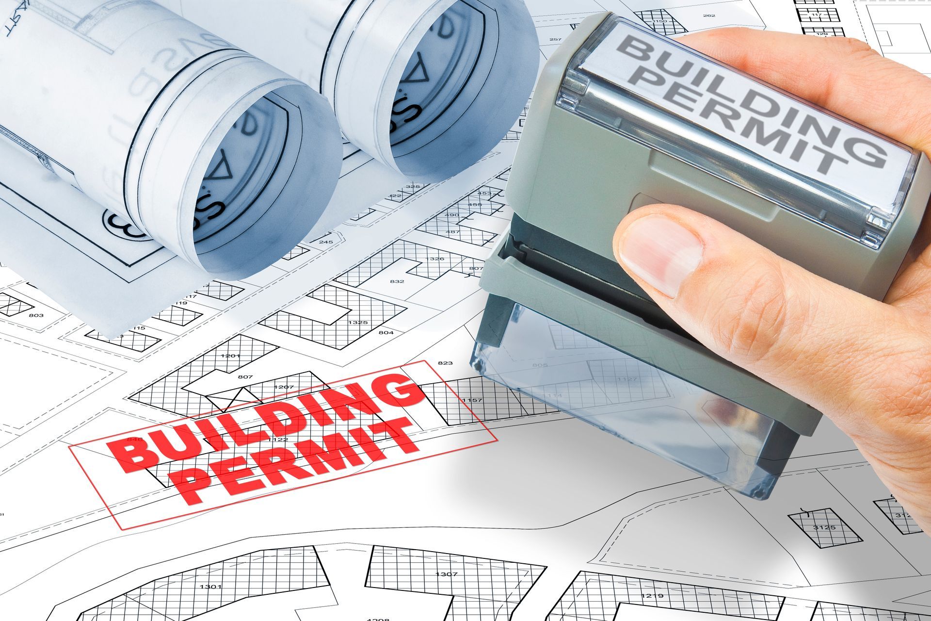 A person is stamping a building permit on a blueprint