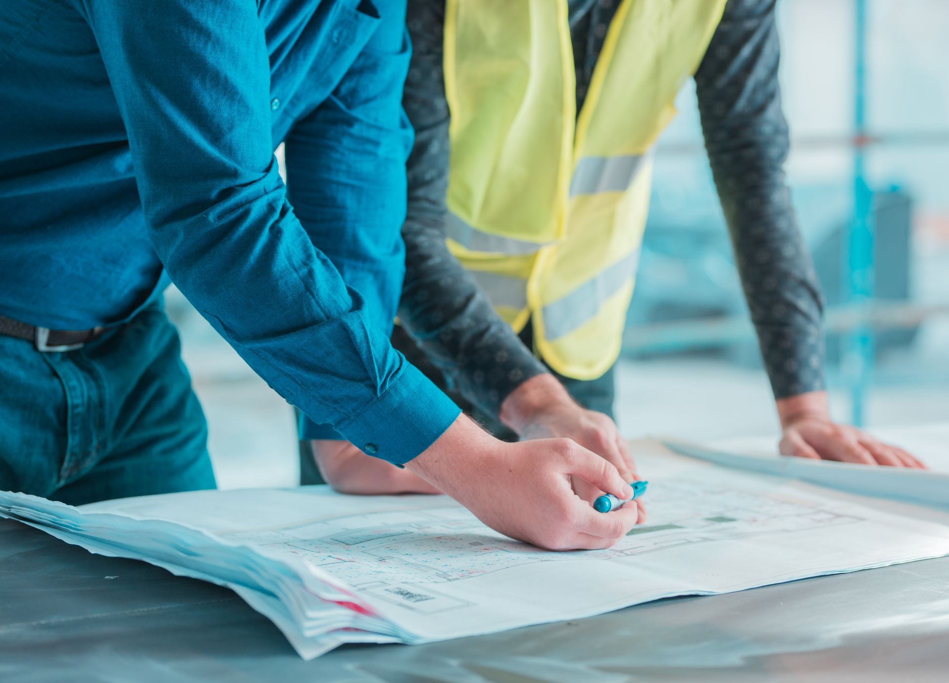 Two men are looking at a blueprint on a table.