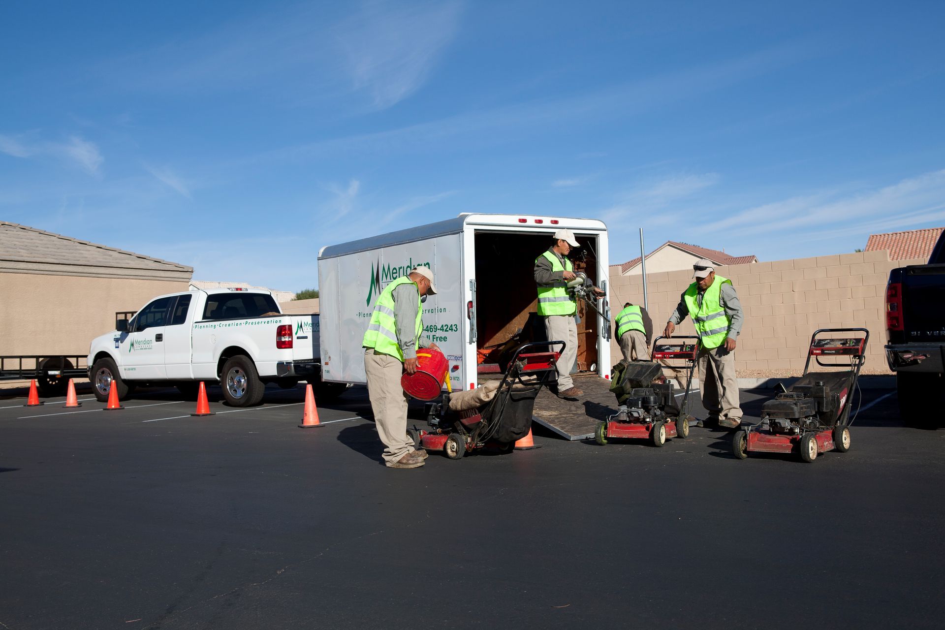 A group of men are working on a lawn mower in front of a trailer.
