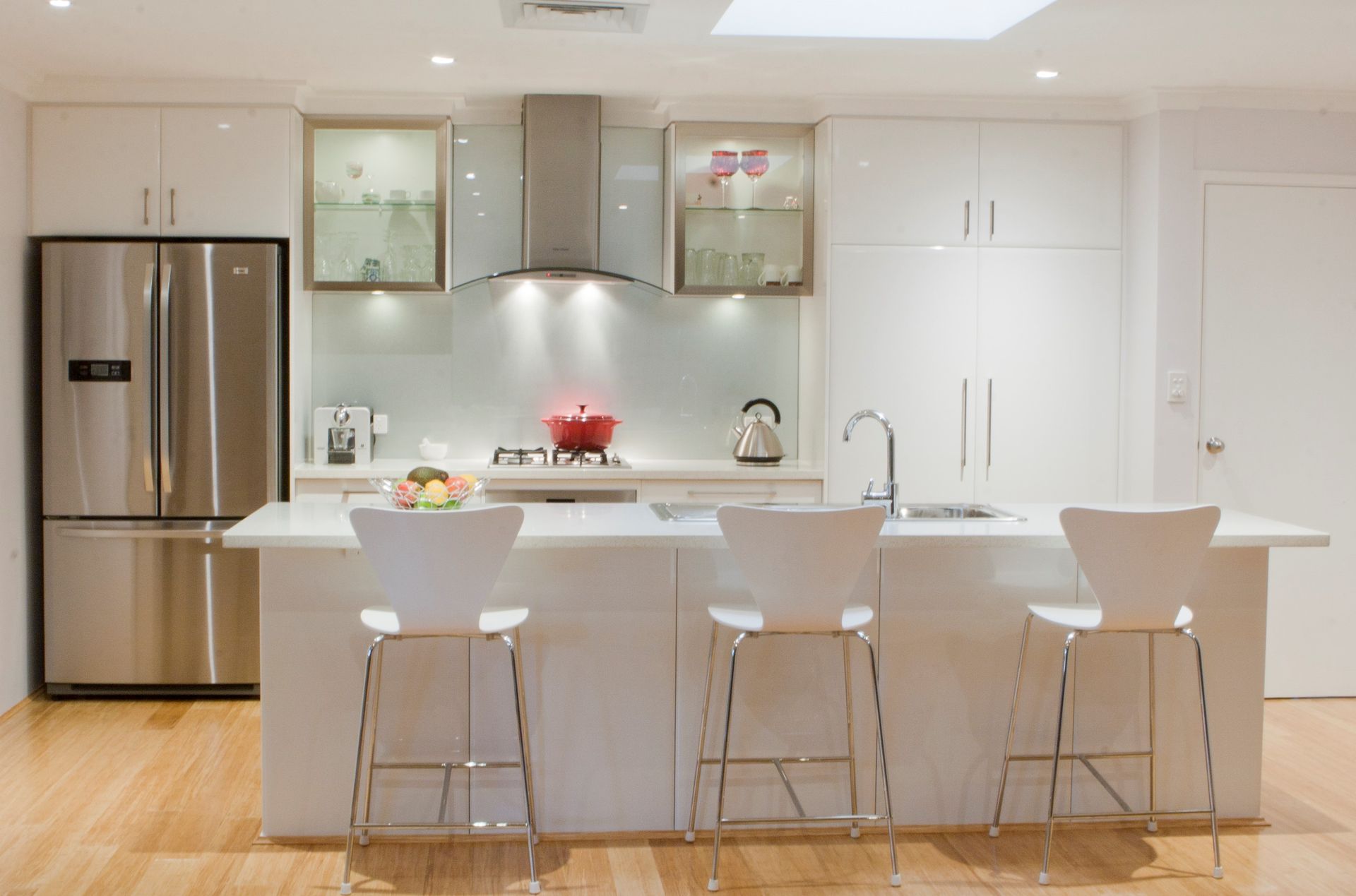 A kitchen with white cabinets and a stainless steel refrigerator