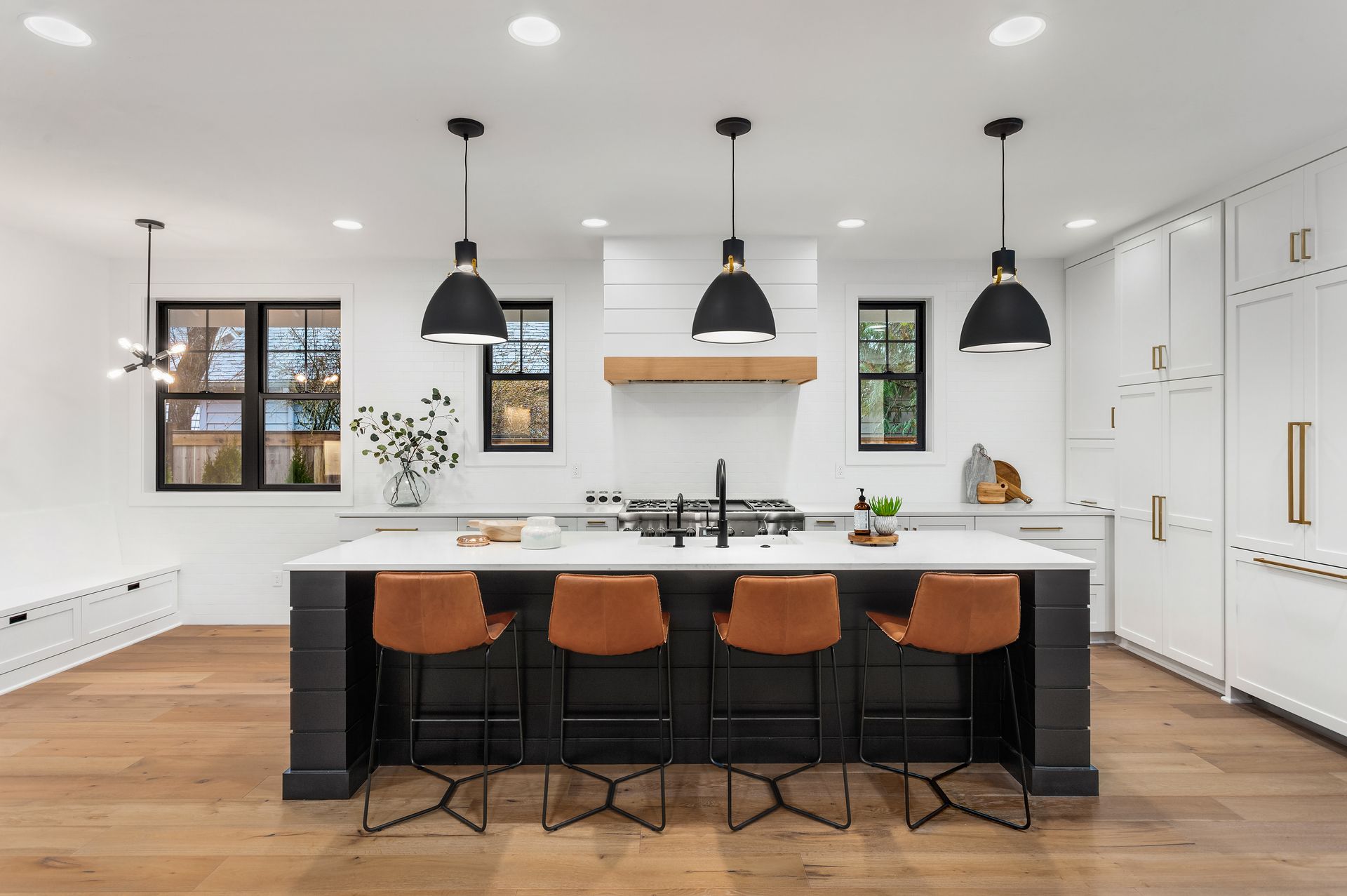 A kitchen with a large island , stools , and a stove.