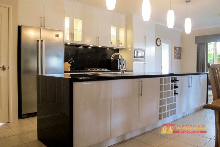 A kitchen with white cabinets and black counter tops