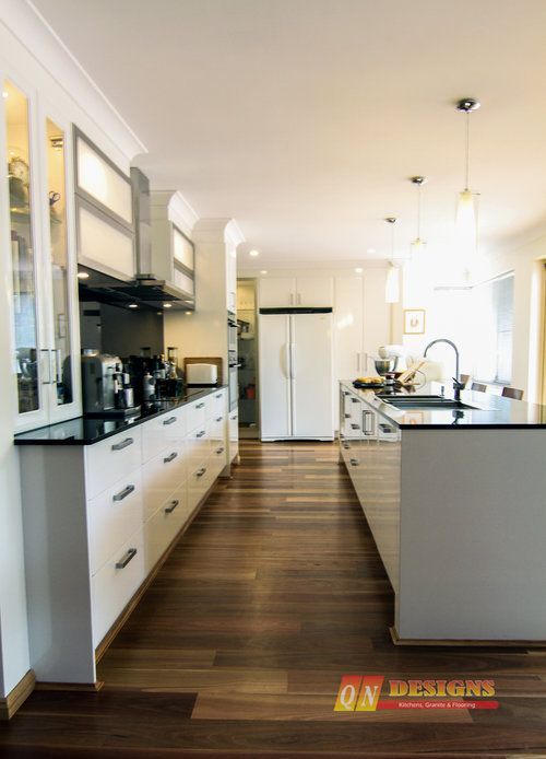 A kitchen with white cabinets and black counter tops