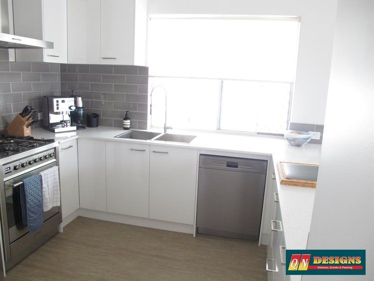 A kitchen with white cabinets and stainless steel appliances